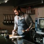 Male chef in a restaurant kitchen preparing a dish, showcasing culinary skills and expertise.